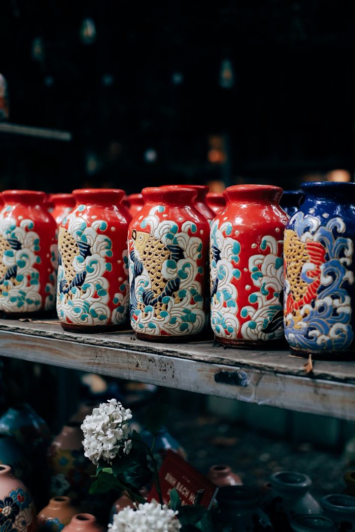 Row of vibrant ceramic vases featuring intricate traditional Asian patterns on a wooden shelf.