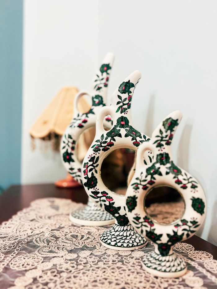 Elegant handmade pottery vases with intricate floral designs displayed on lace for aesthetic decor.
